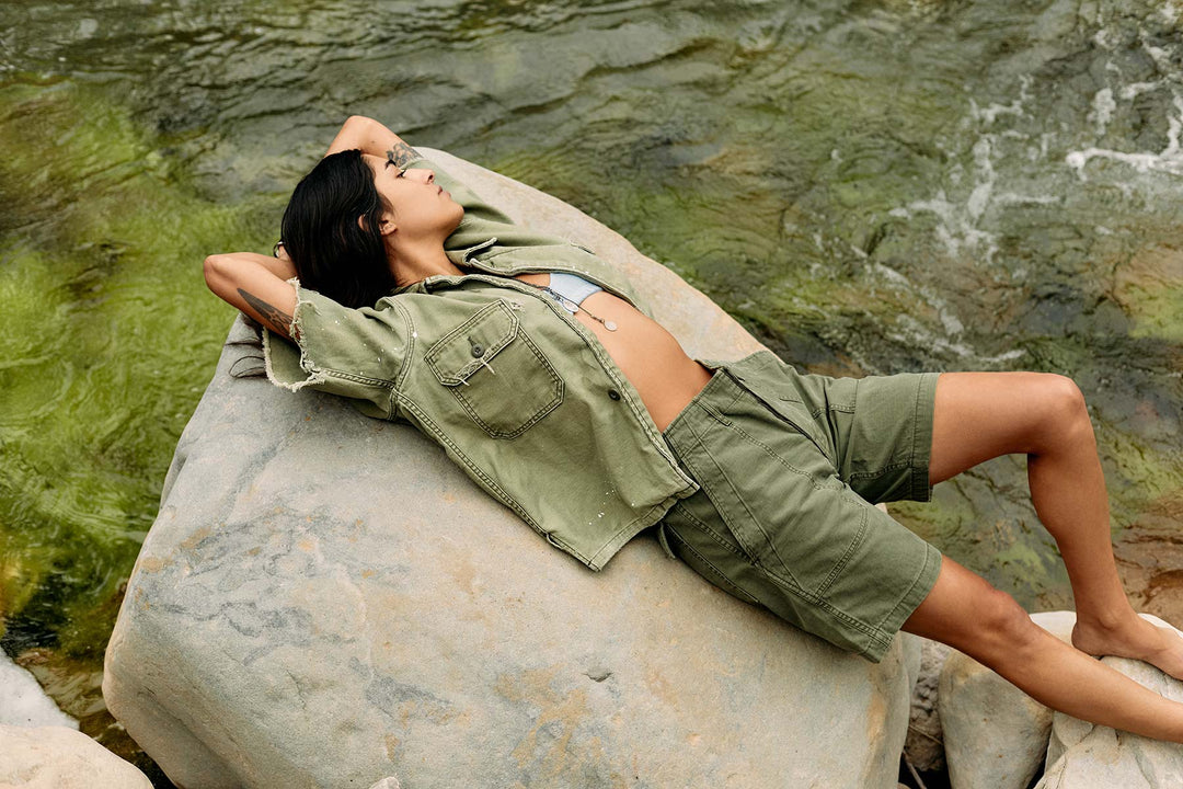 a woman lying on a rock by water