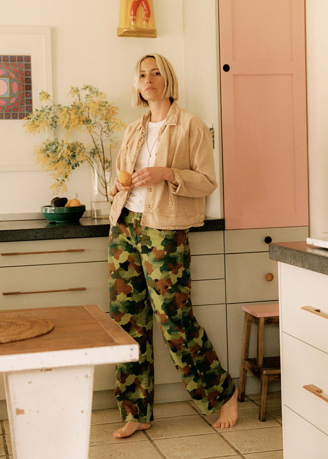 a woman in camouflage pants holding an orange