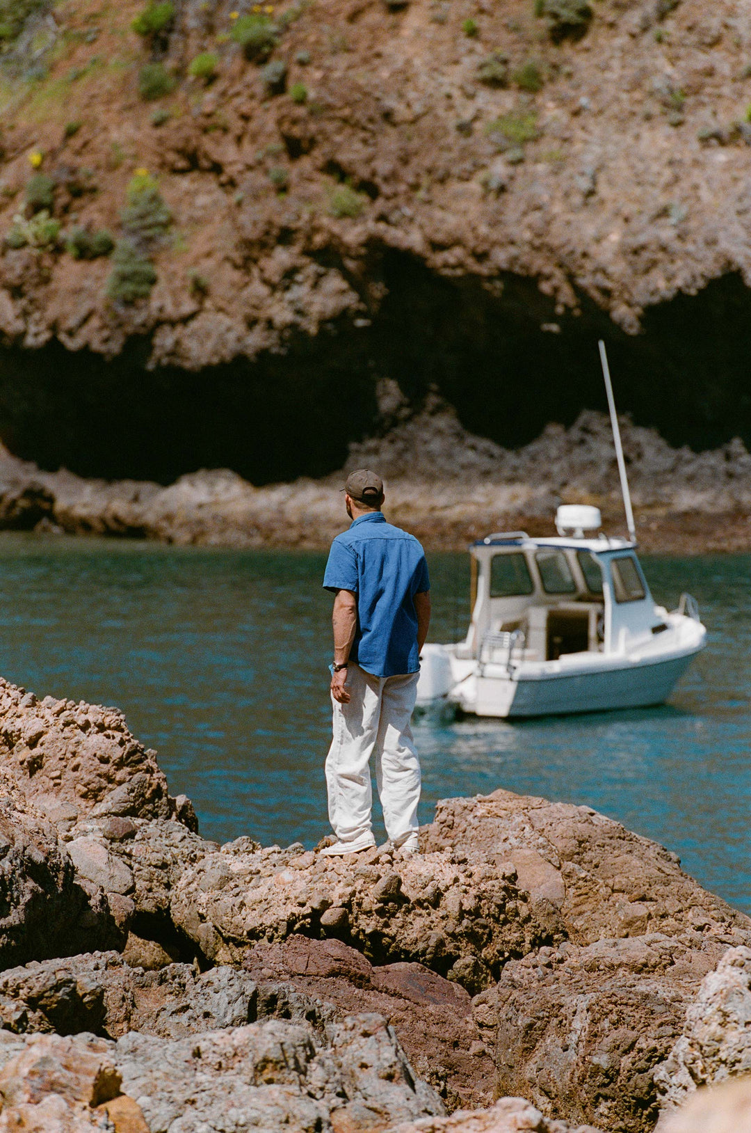 a man standing on a rock near a boat