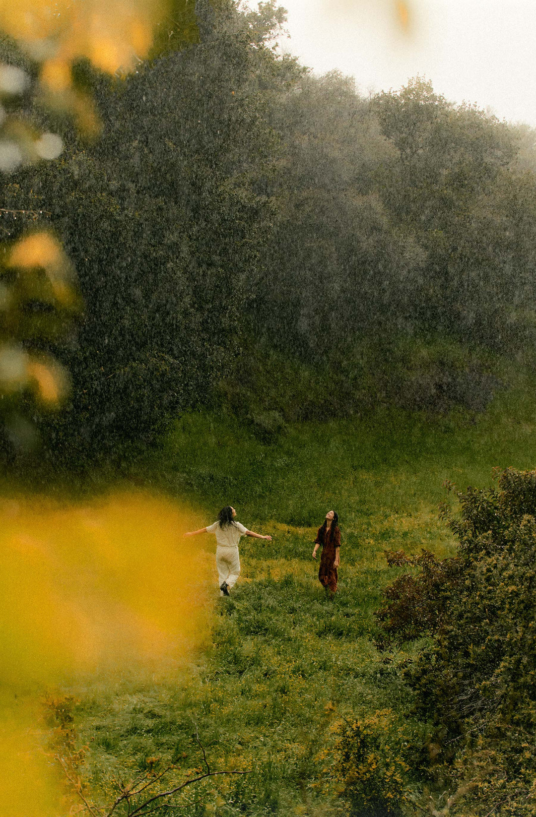 two women running in a field in the rain