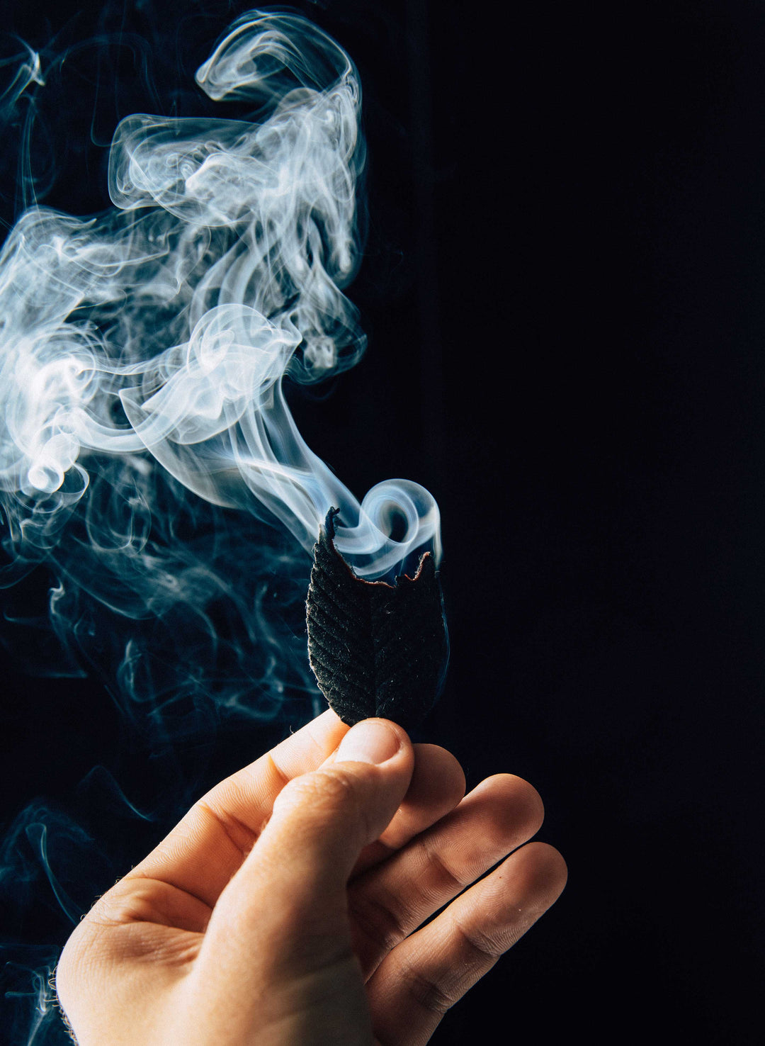 a hand holding a black object with smoke coming out of it