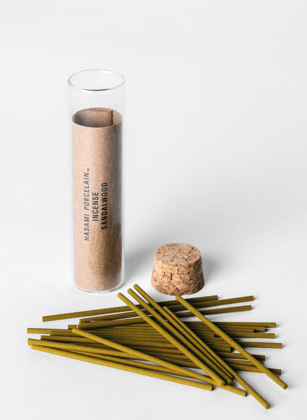 a group of green sticks next to a tube of sandalwood