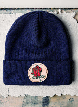 a blue beanie with a rose patch