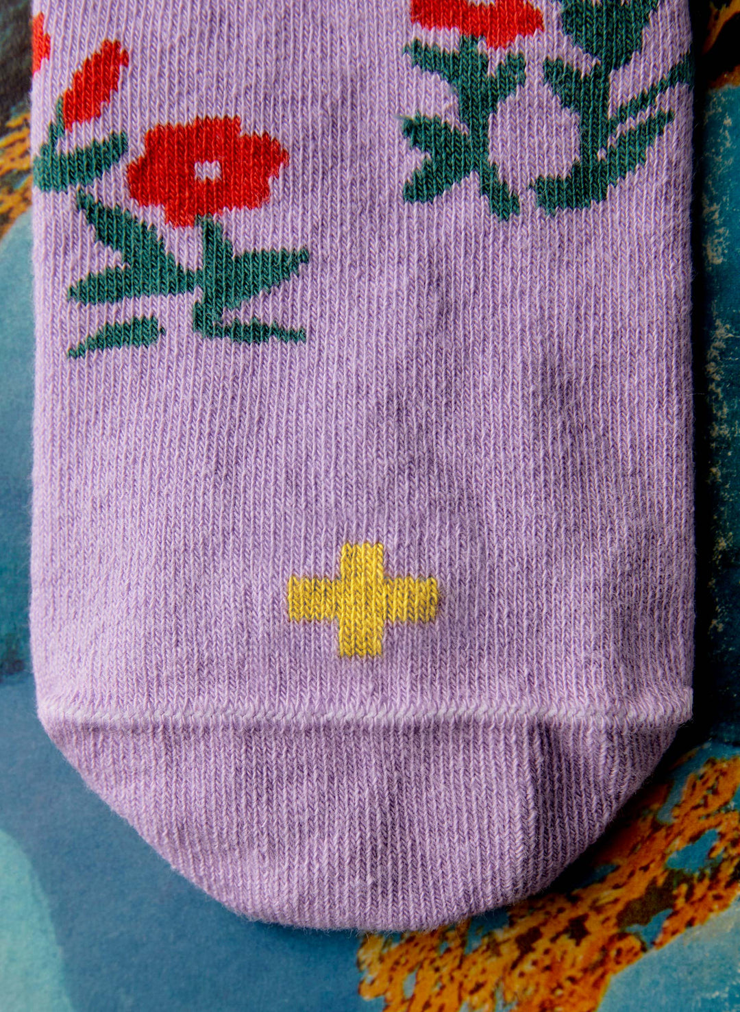 a purple sock with a flower and a yellow cross on it