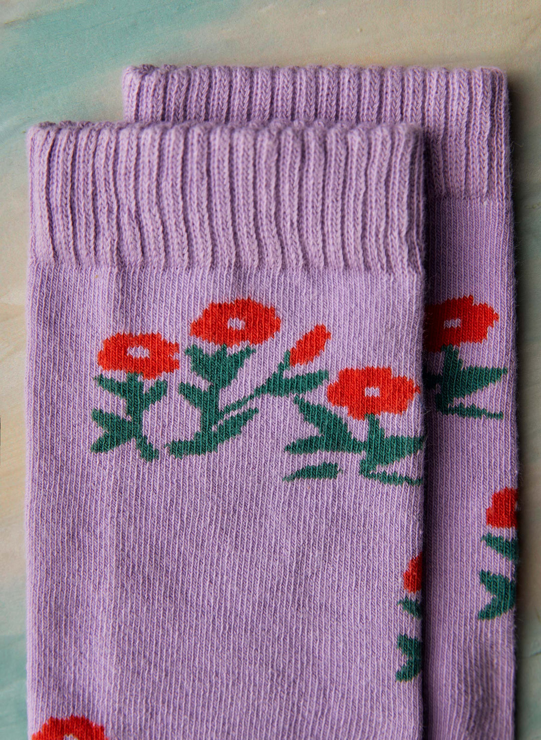 a pair of purple socks with red flowers on them