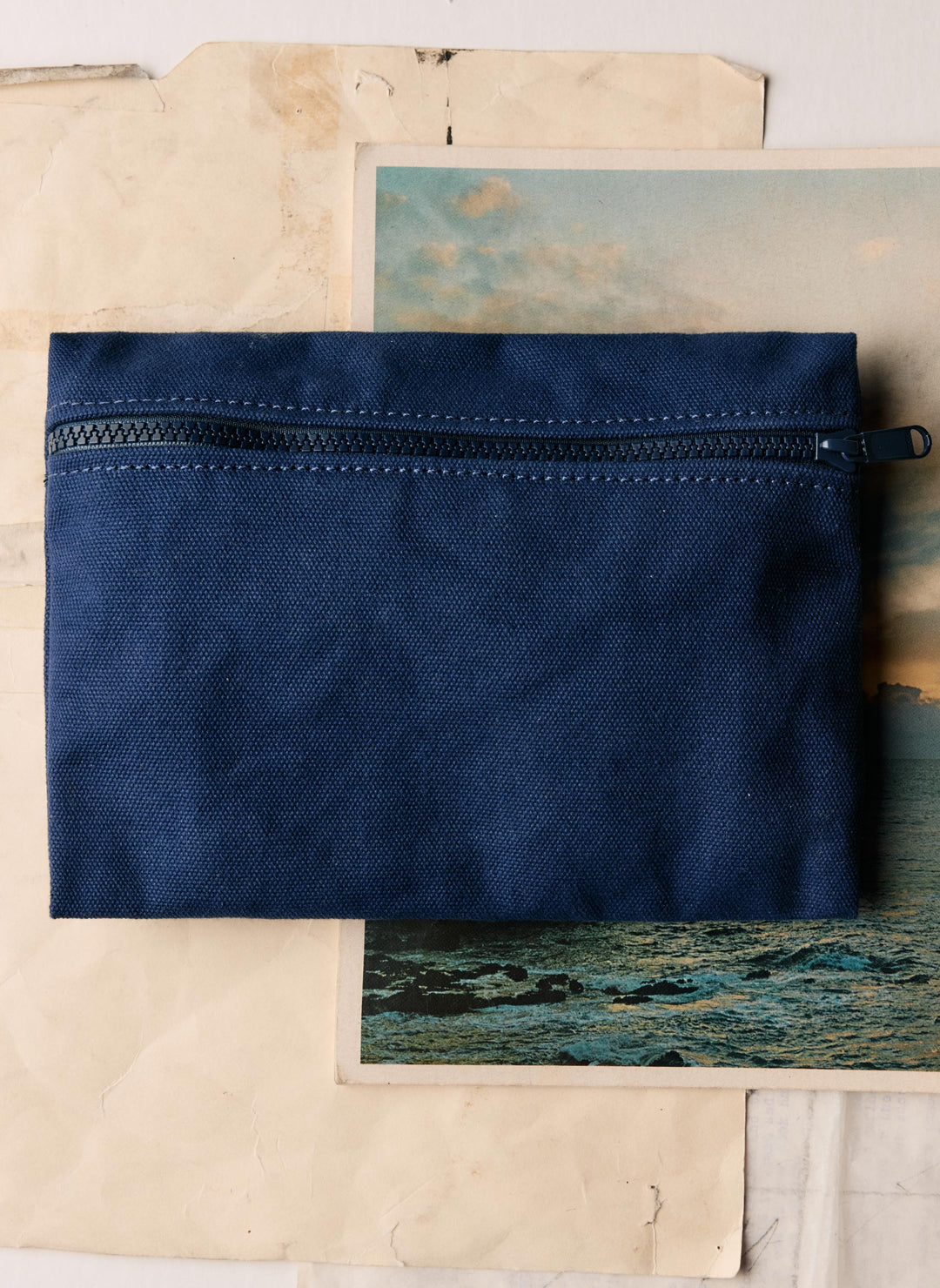 a blue zippered pouch on a paper