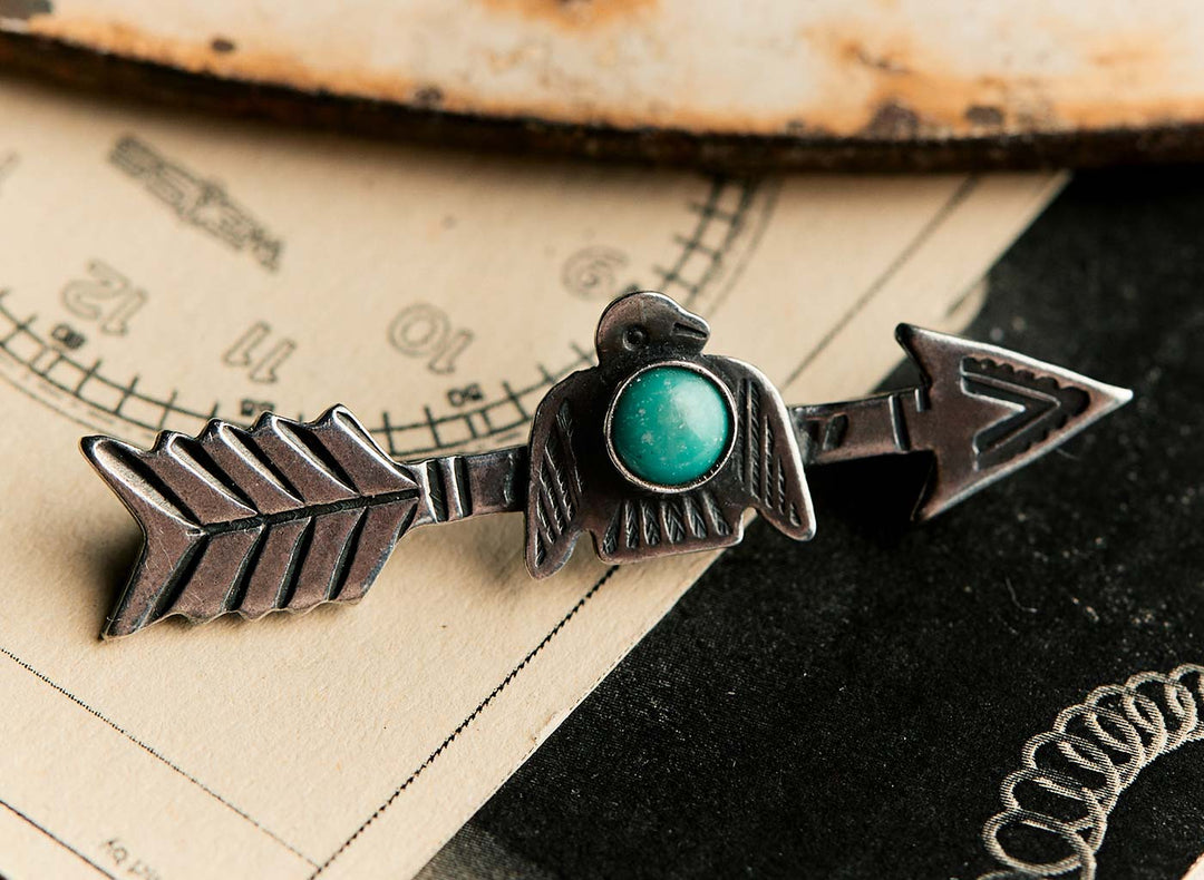 a metal arrow pin with a blue stone in the middle