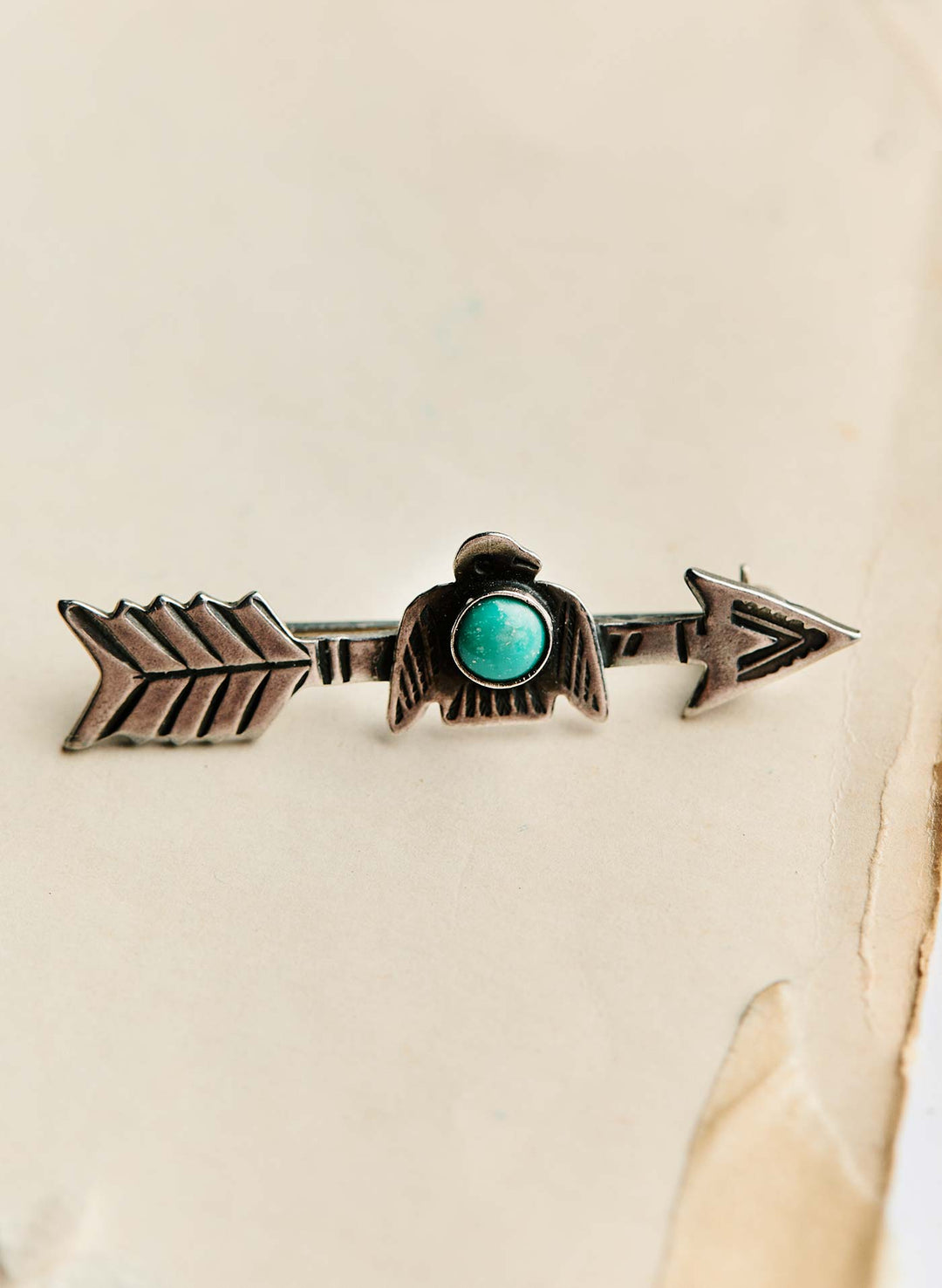 a silver arrow pin with a blue stone