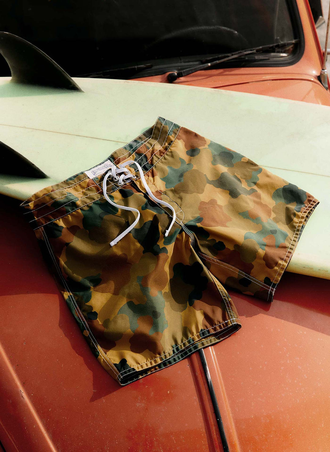 a camouflage swim shorts on a surfboard