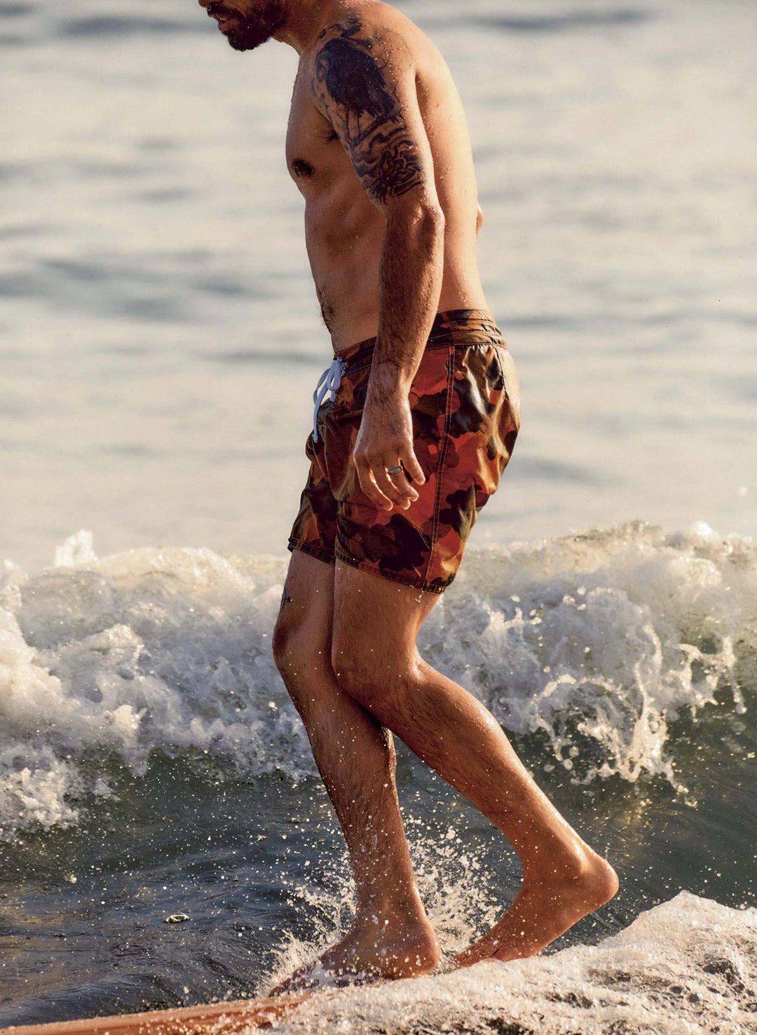 a man in swim trunks walking on a wave