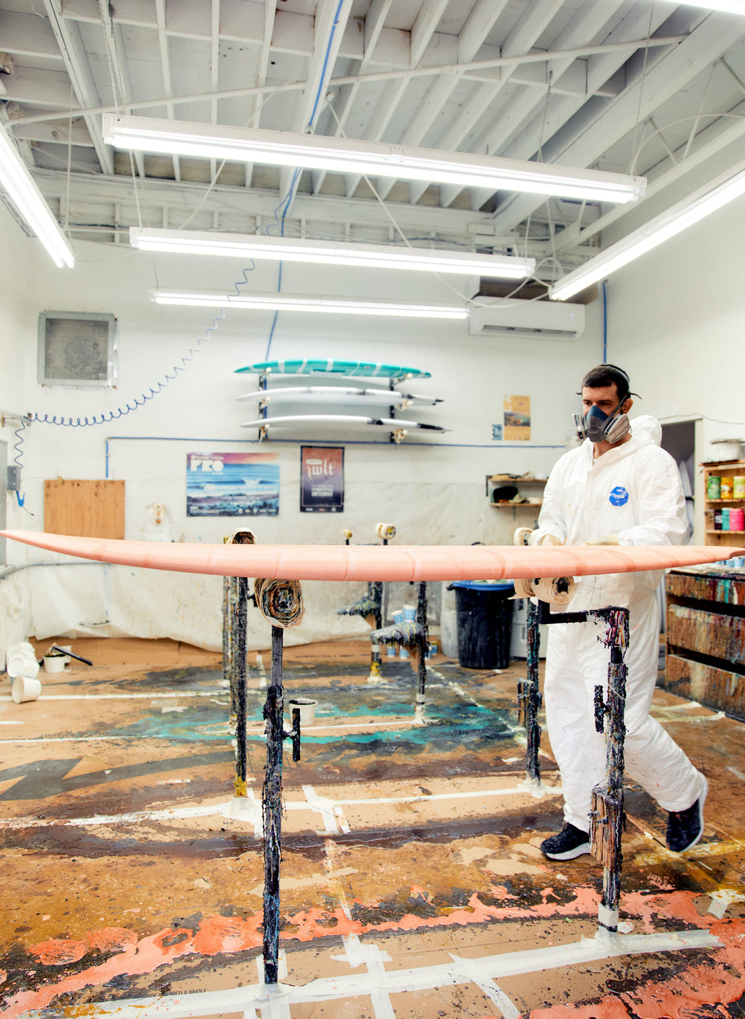 a man in a white suit painting a surfboard