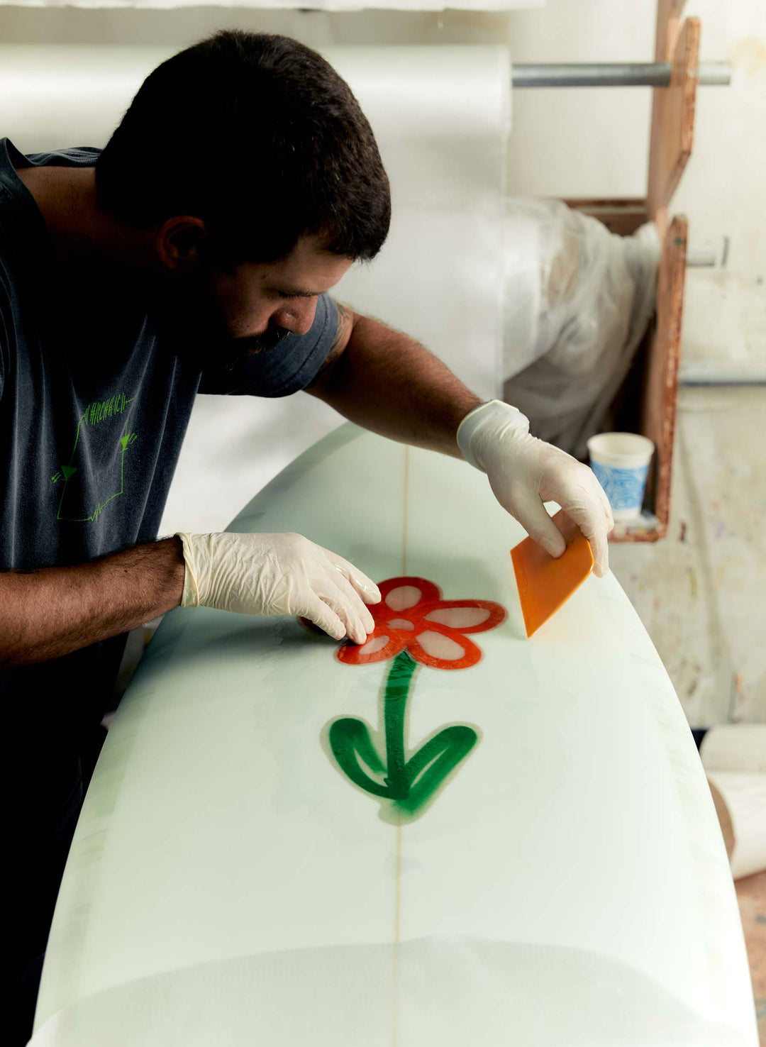 a man painting a flower on a surfboard