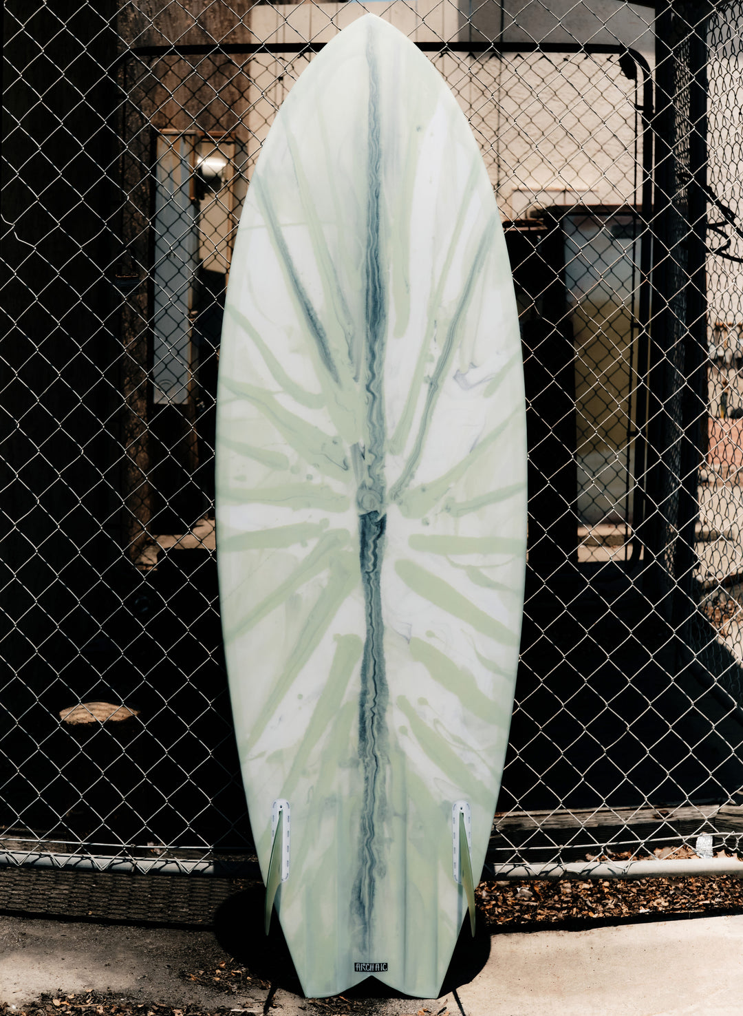 a white surfboard leaning against a fence