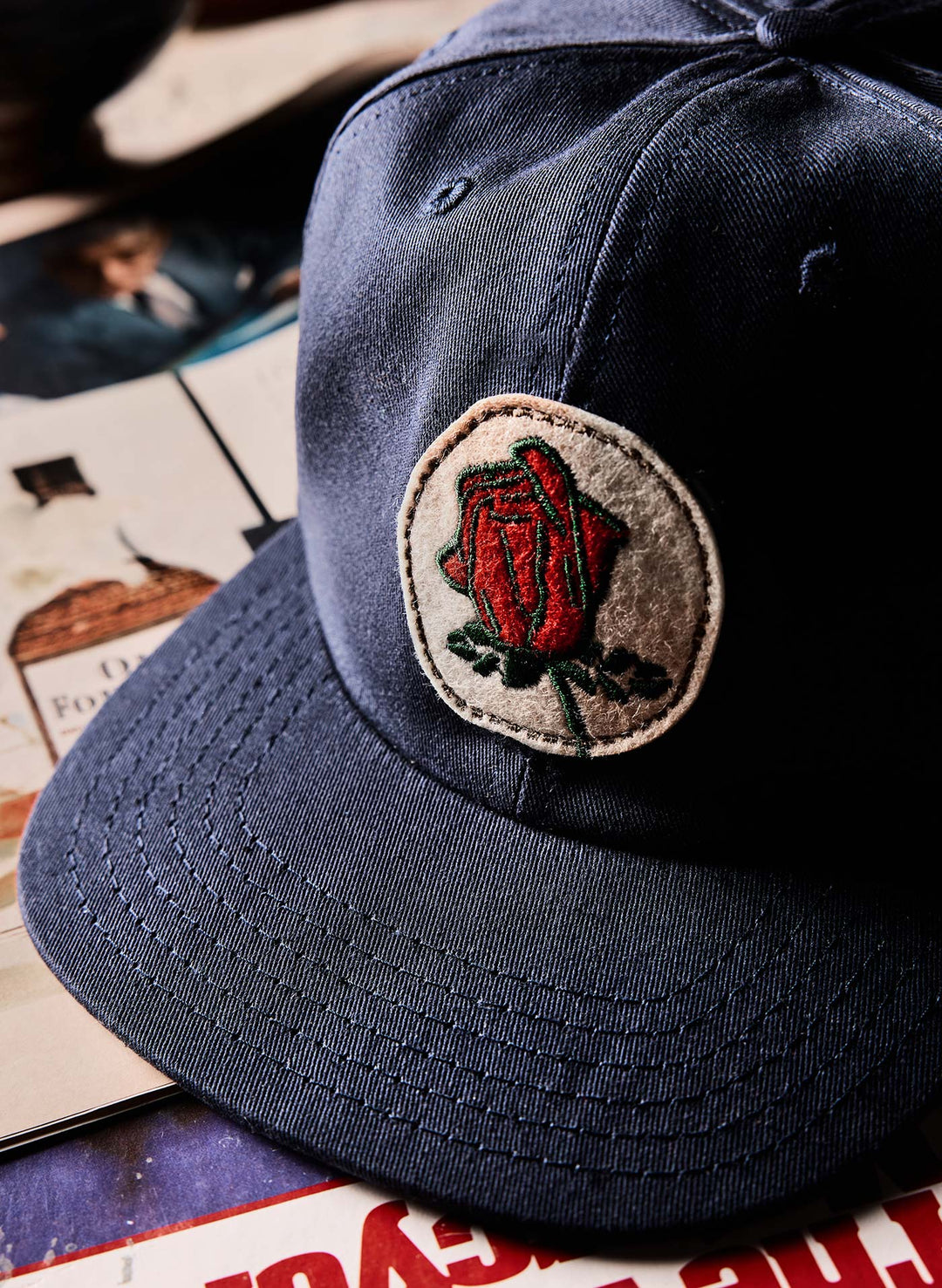 a blue hat with a rose patch on it