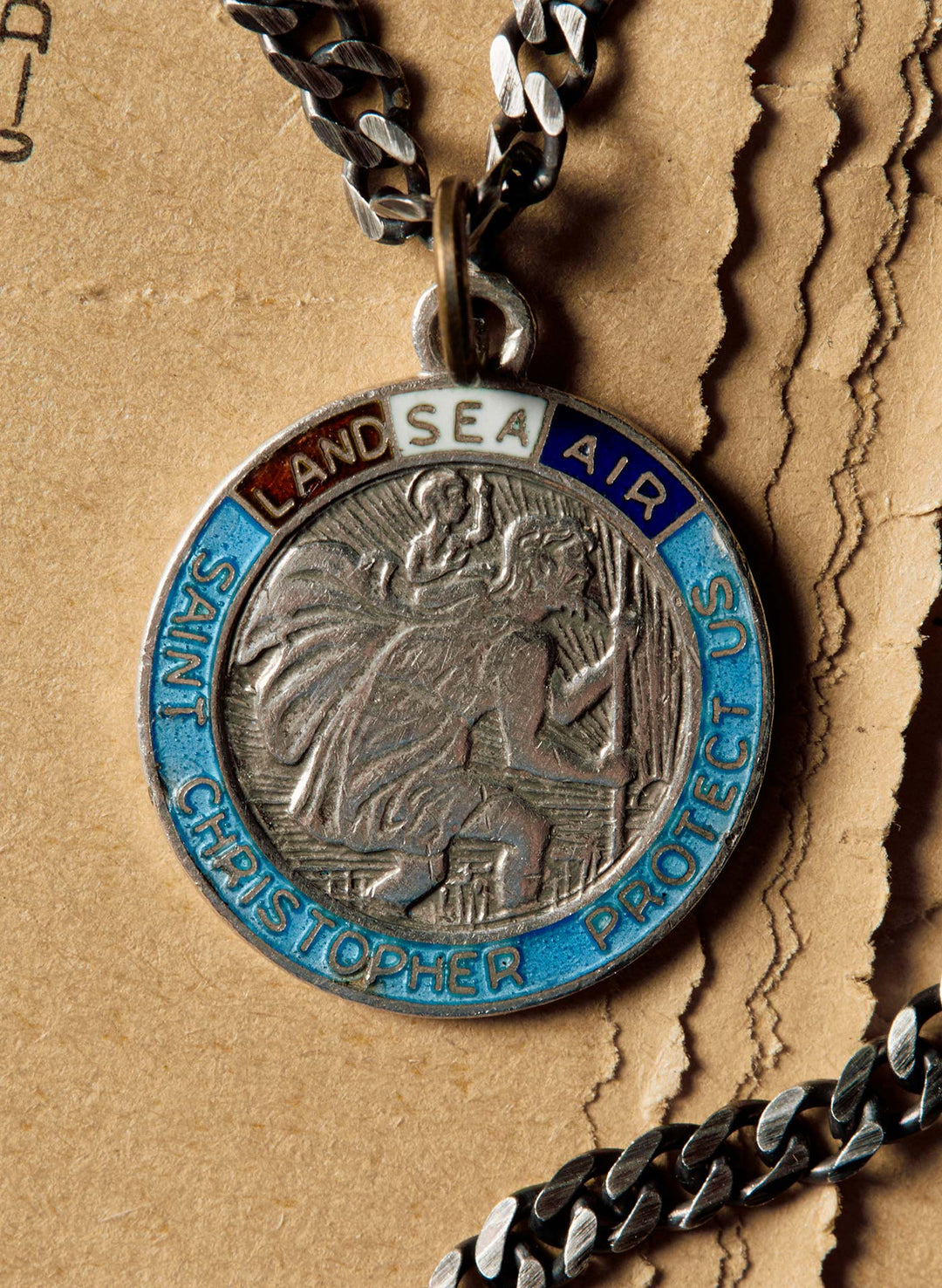 a silver medallion with blue and white text on a chain