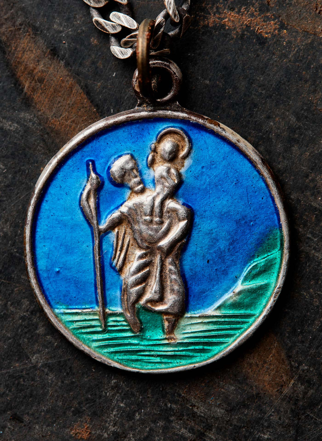 a round blue and green medallion with a man carrying a woman on his back