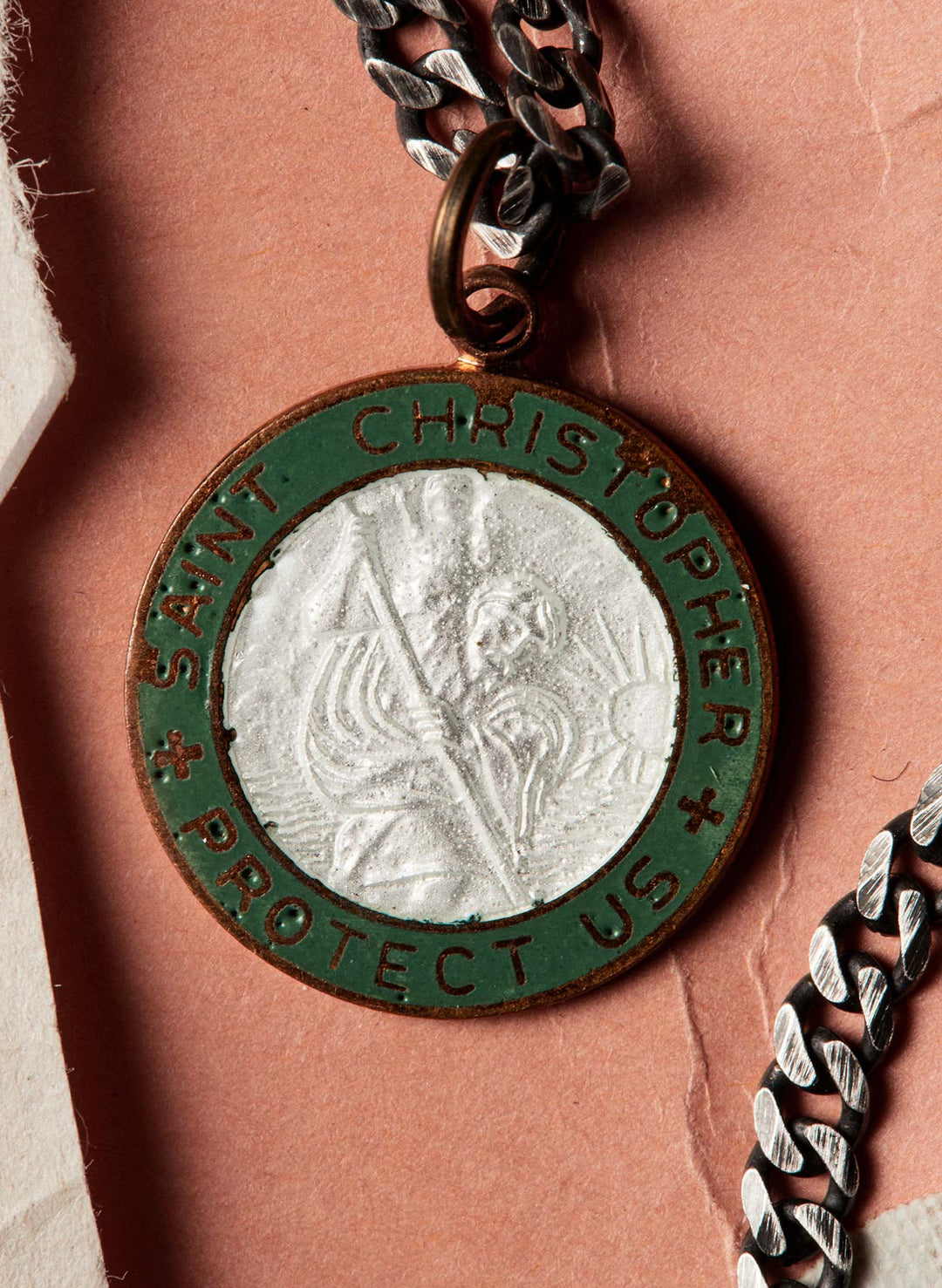 a silver and green medallion with a silver chain