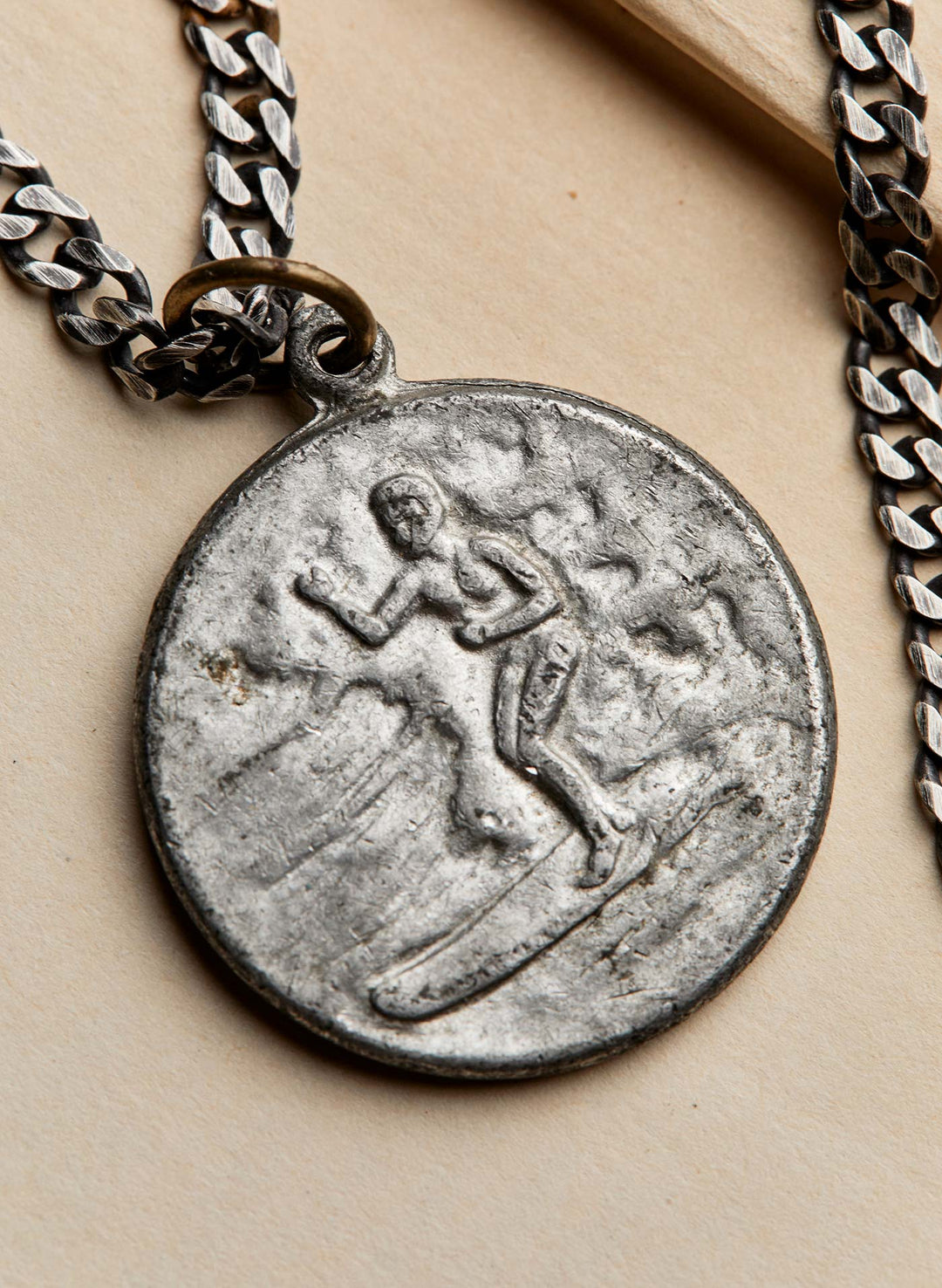 a silver medallion with a person on a chain