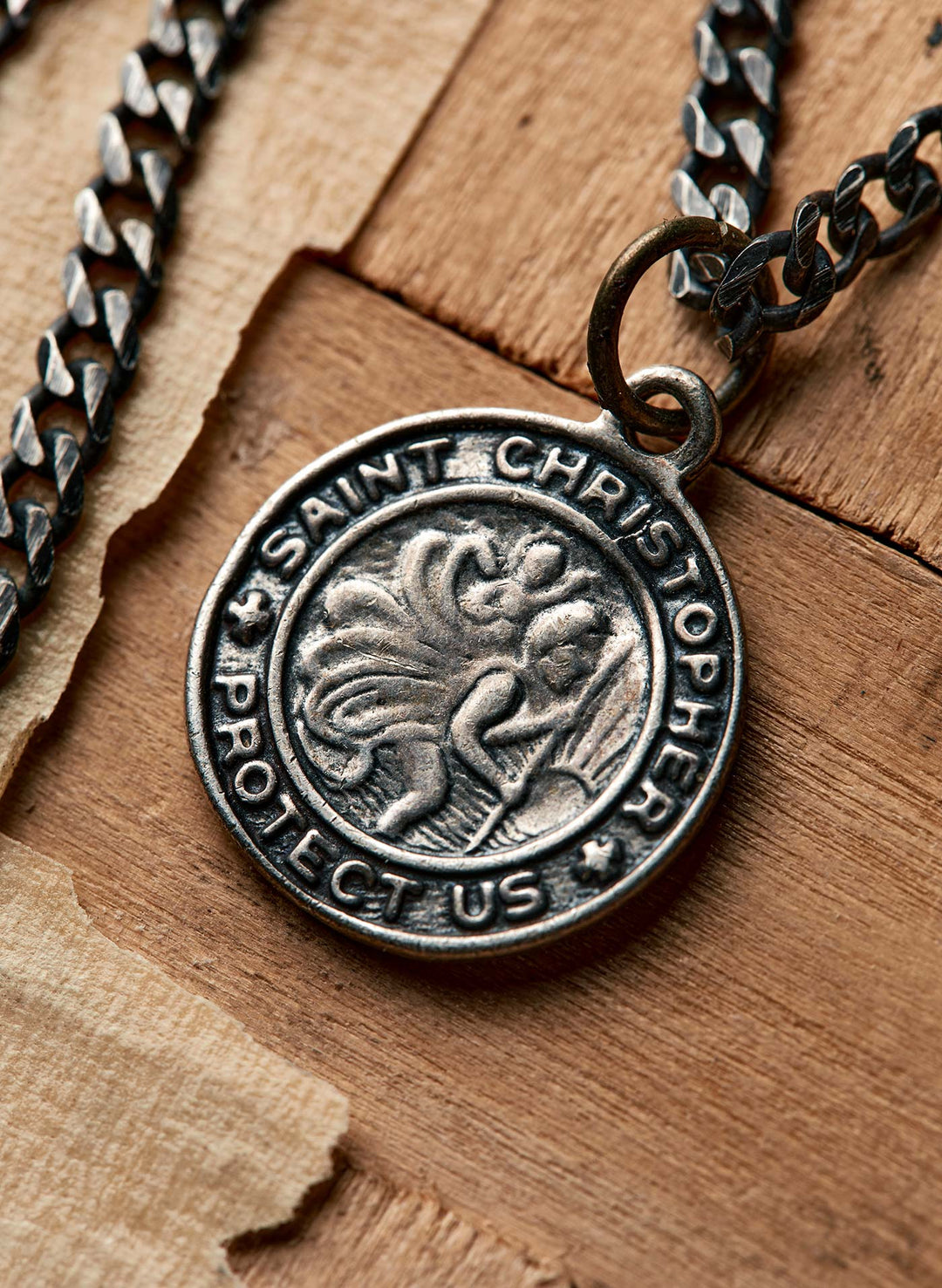 a silver medallion with a chain on a wood surface