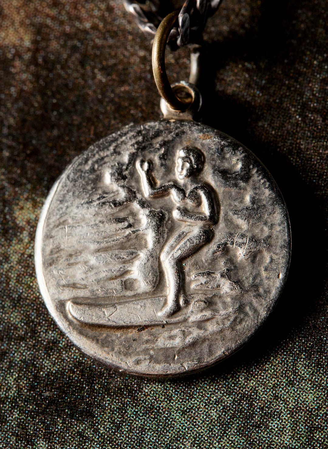 a silver medallion with a picture of a man on a chain