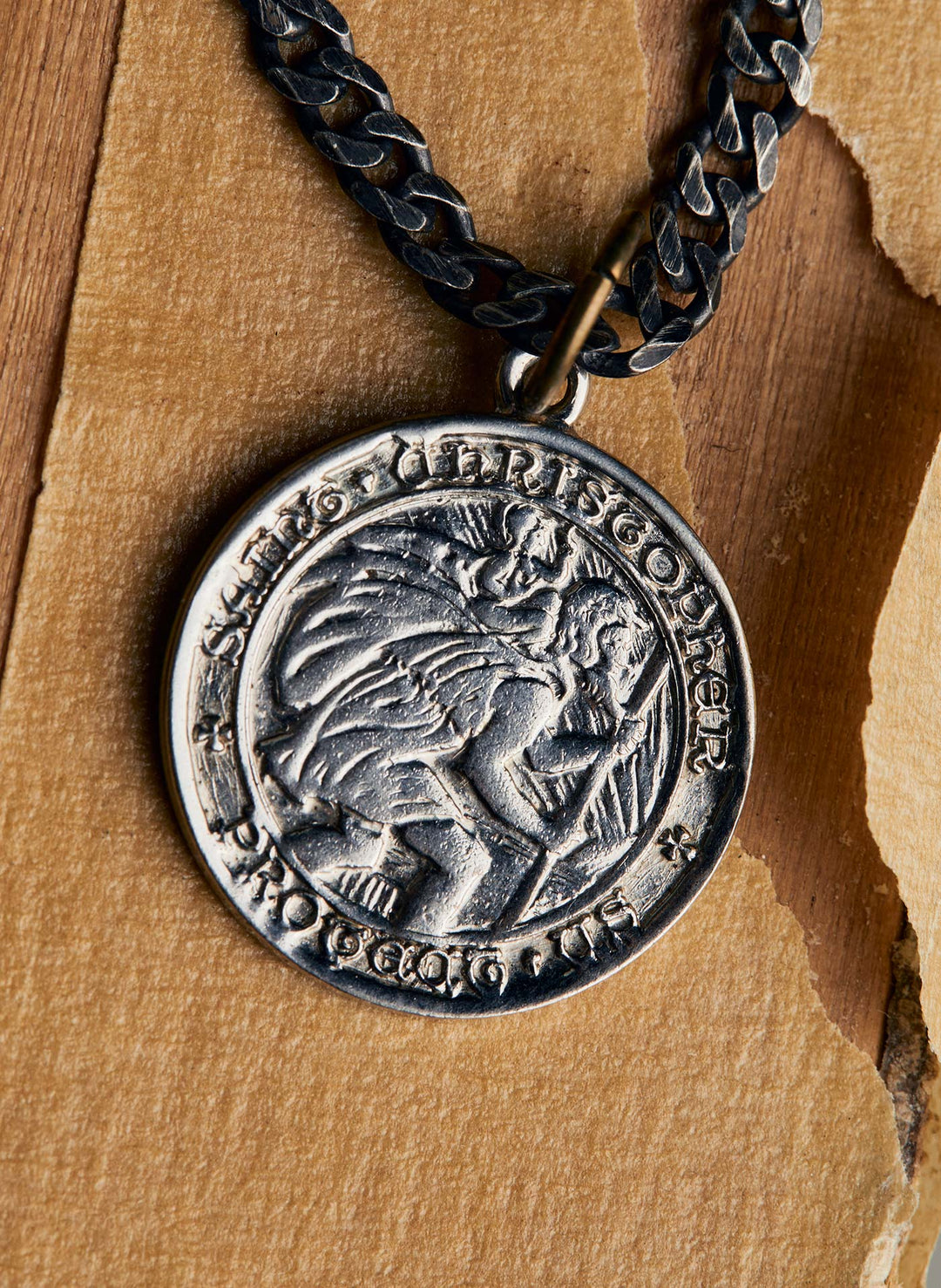 a silver coin with a chain on a wood surface