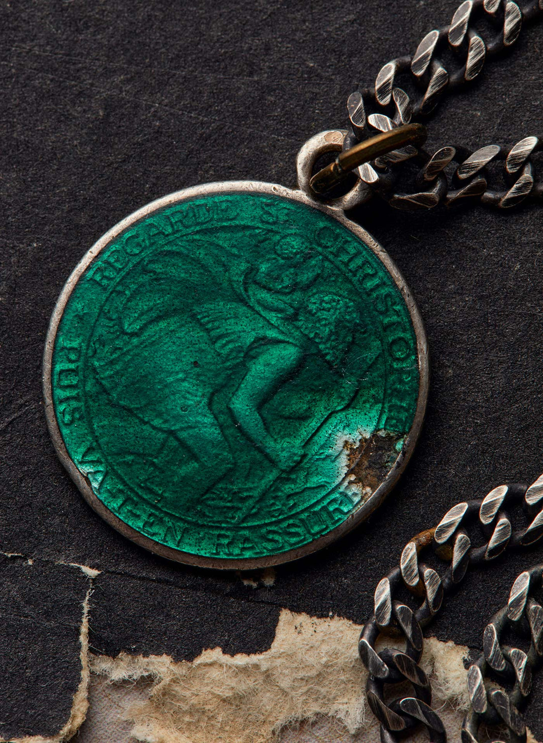 a green medallion with a chain