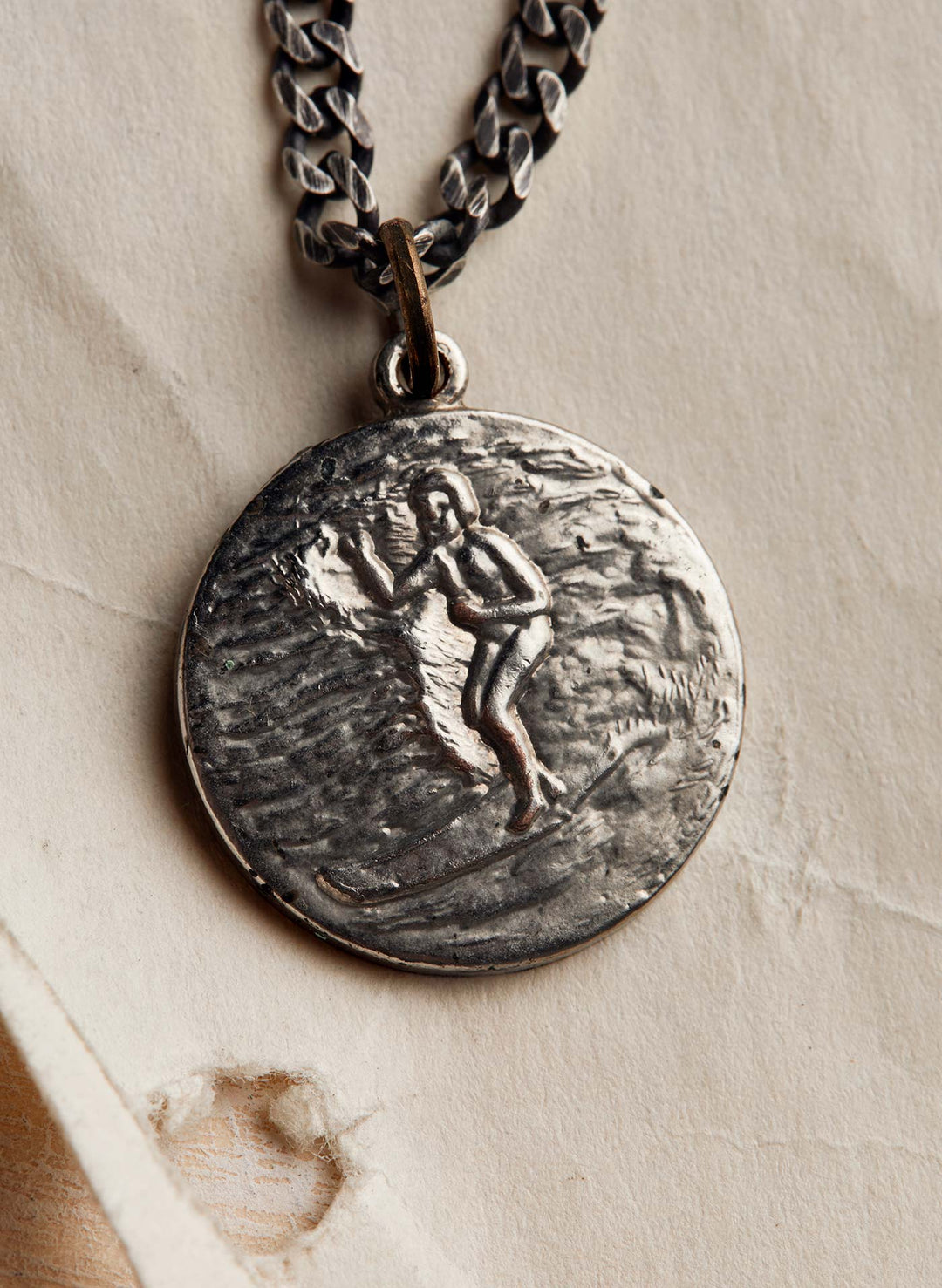 a silver medallion with a person on a chain