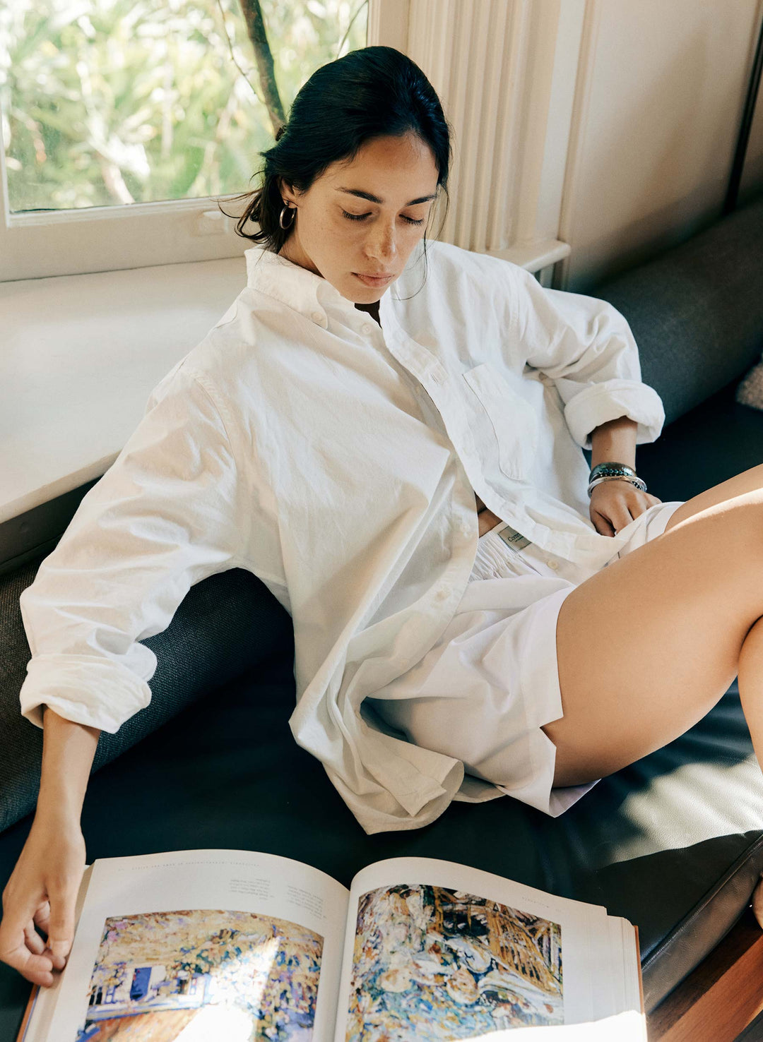 a woman sitting on a couch reading a book