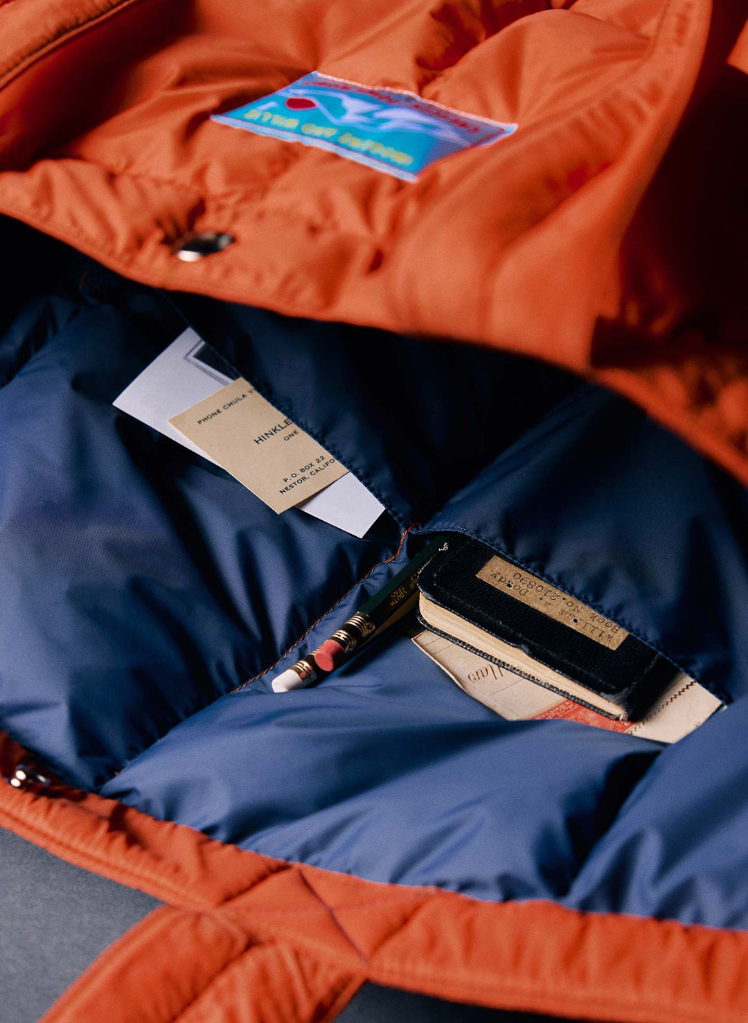 a blue and orange jacket with a pen and a book inside