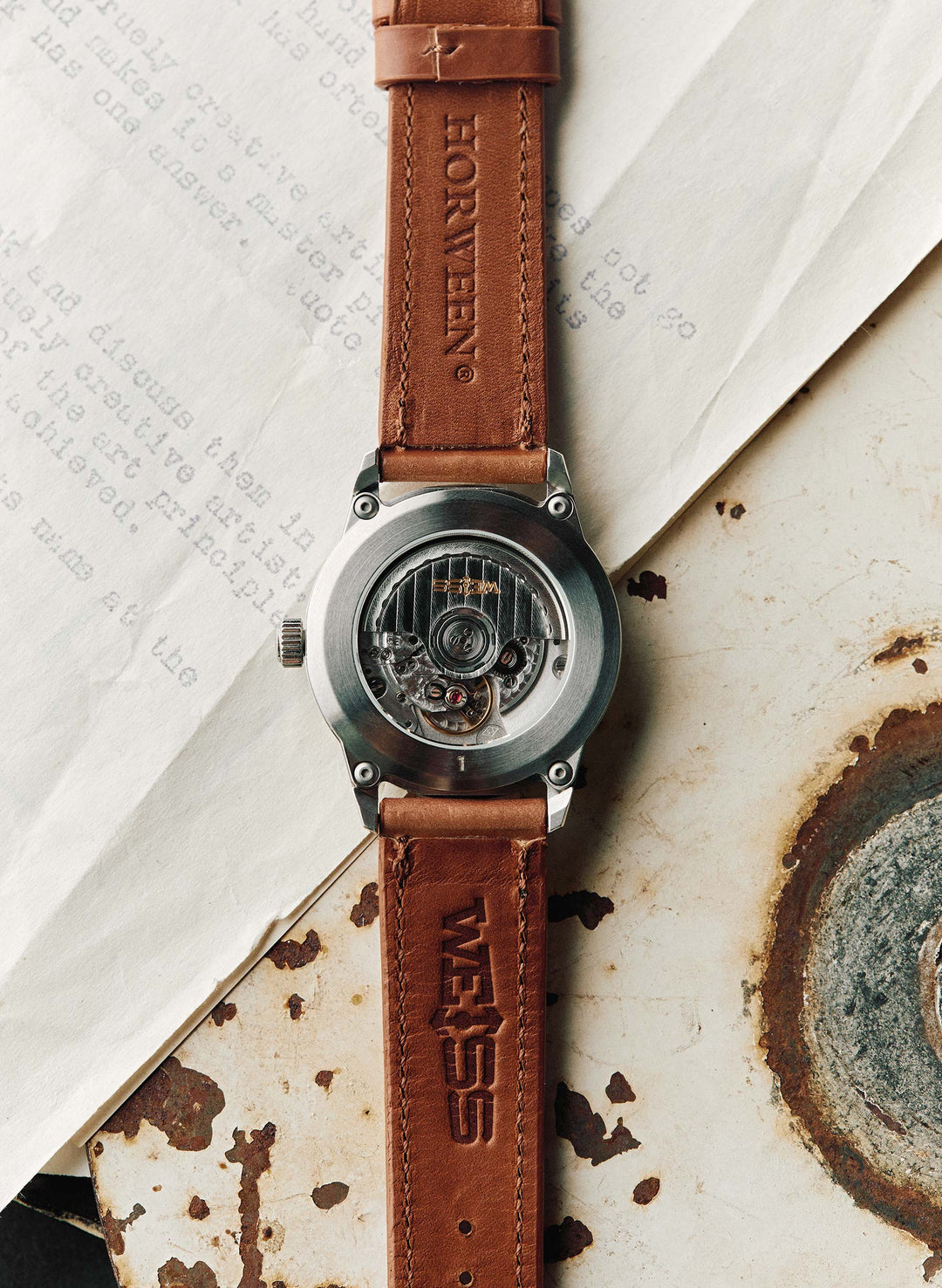 a watch with leather strap on top of a piece of paper