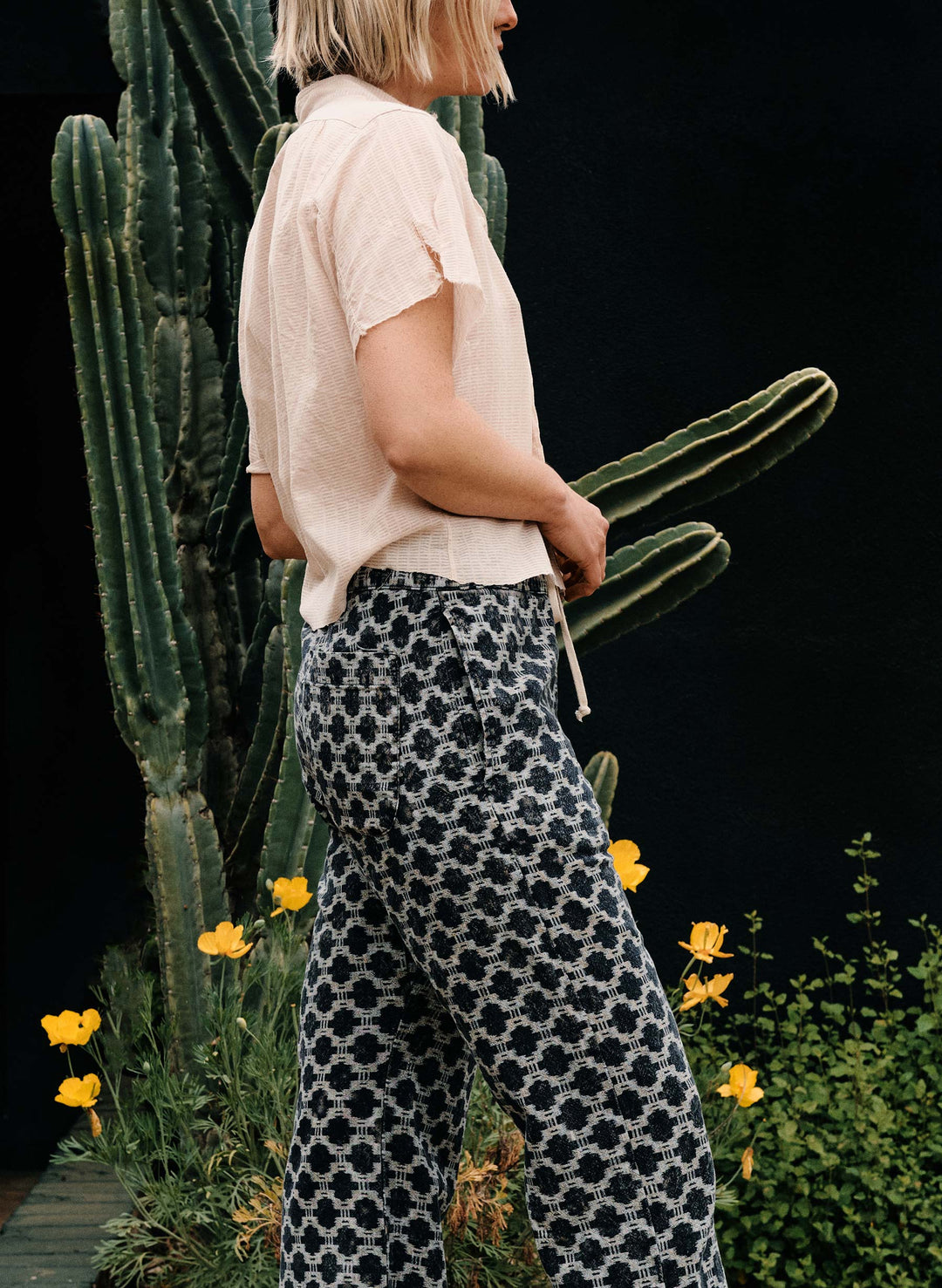 a woman standing next to a cactus