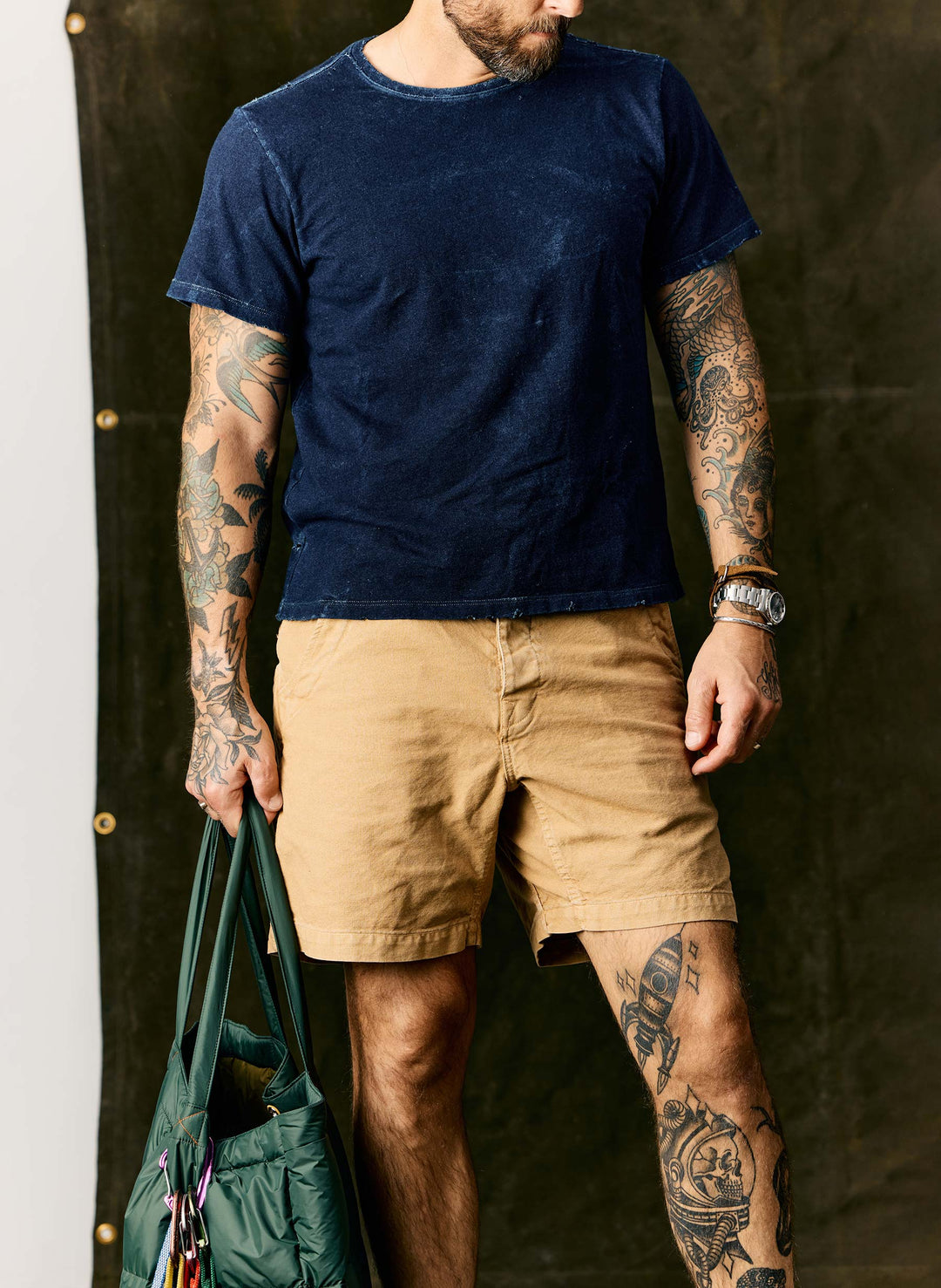 a man with tattoos on his arms and a bag