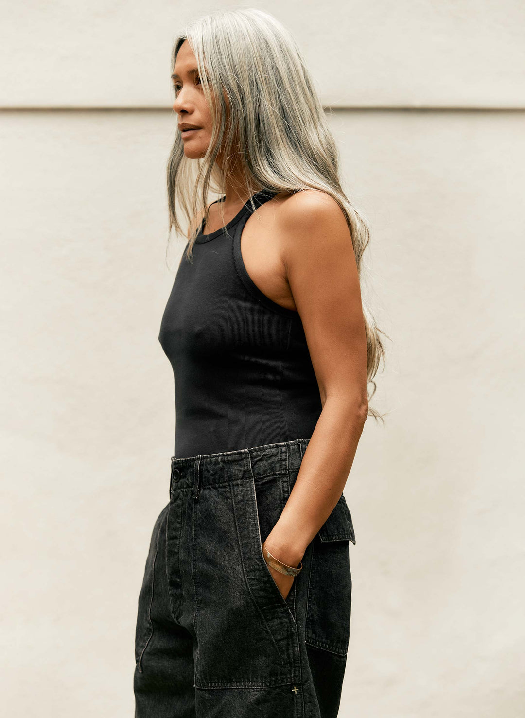 a woman with long hair wearing a tank top and black shorts