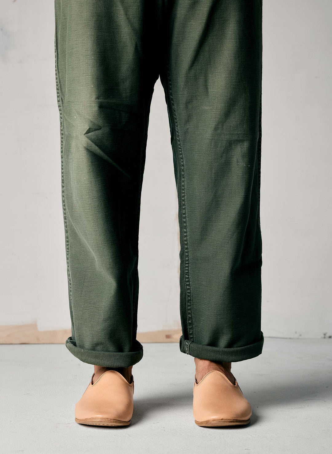 a person wearing green pants and tan shoes