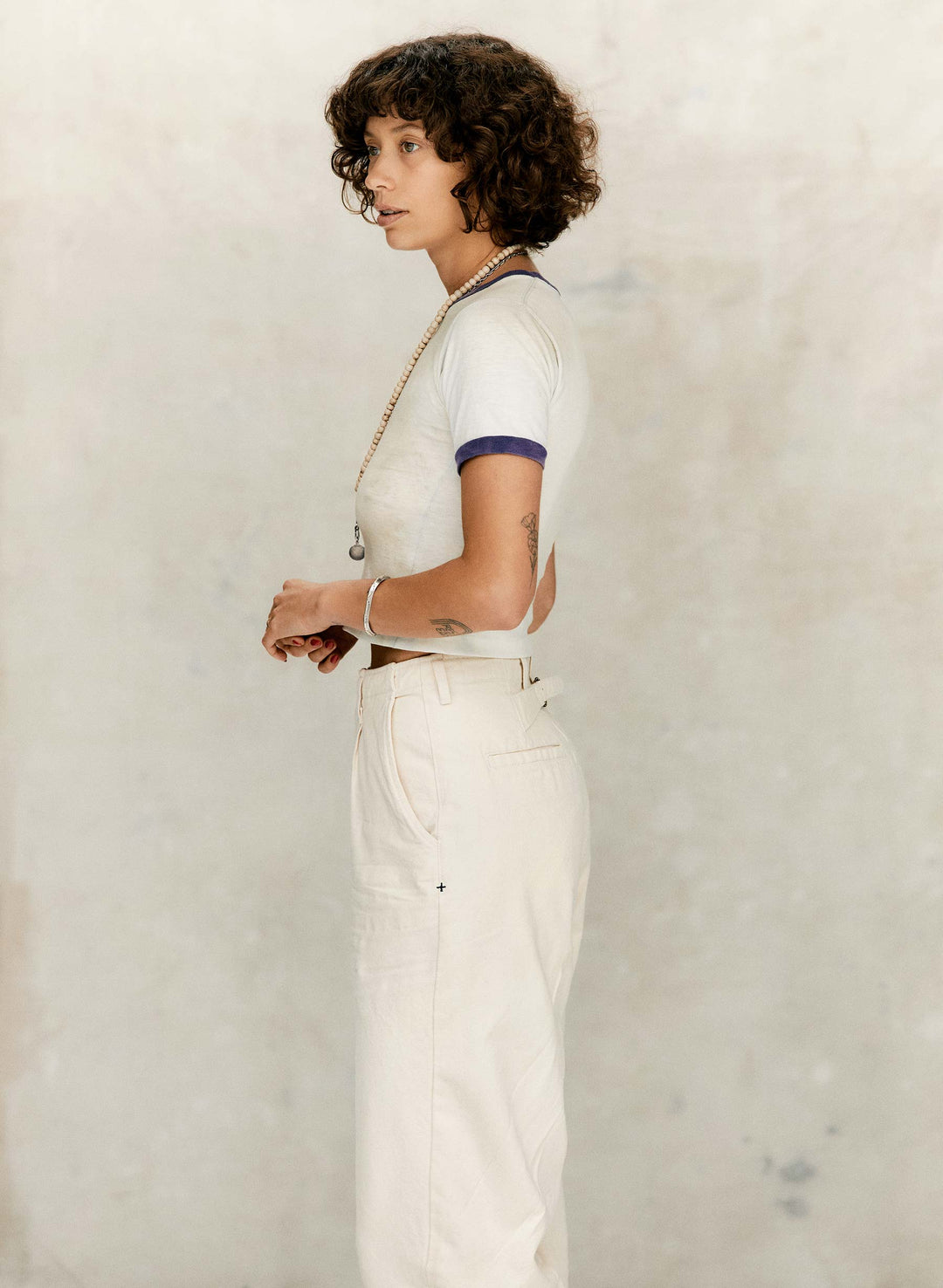 a woman with curly hair wearing white pants and a white shirt