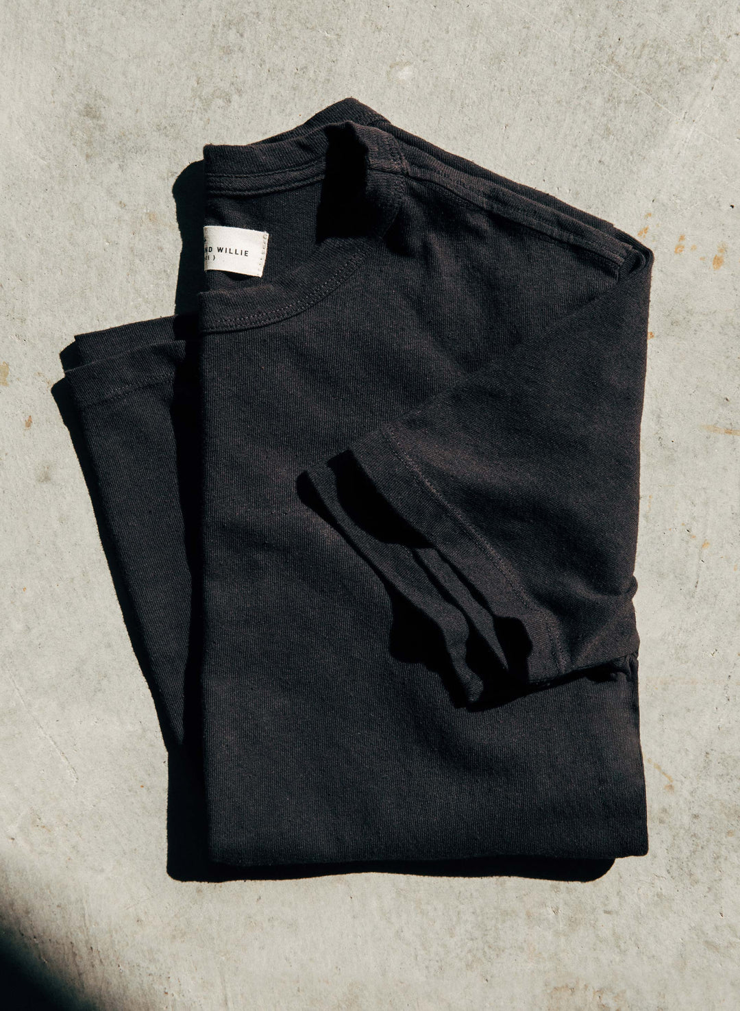 a folded black sweater on a concrete surface