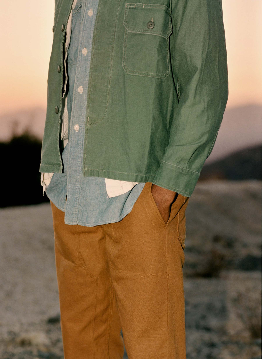 a man wearing a green jacket and brown pants