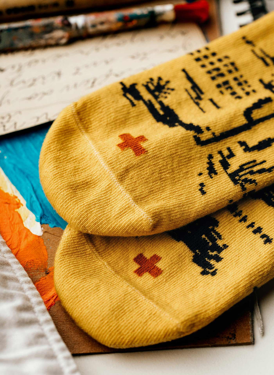 a pair of yellow socks with a red cross on them