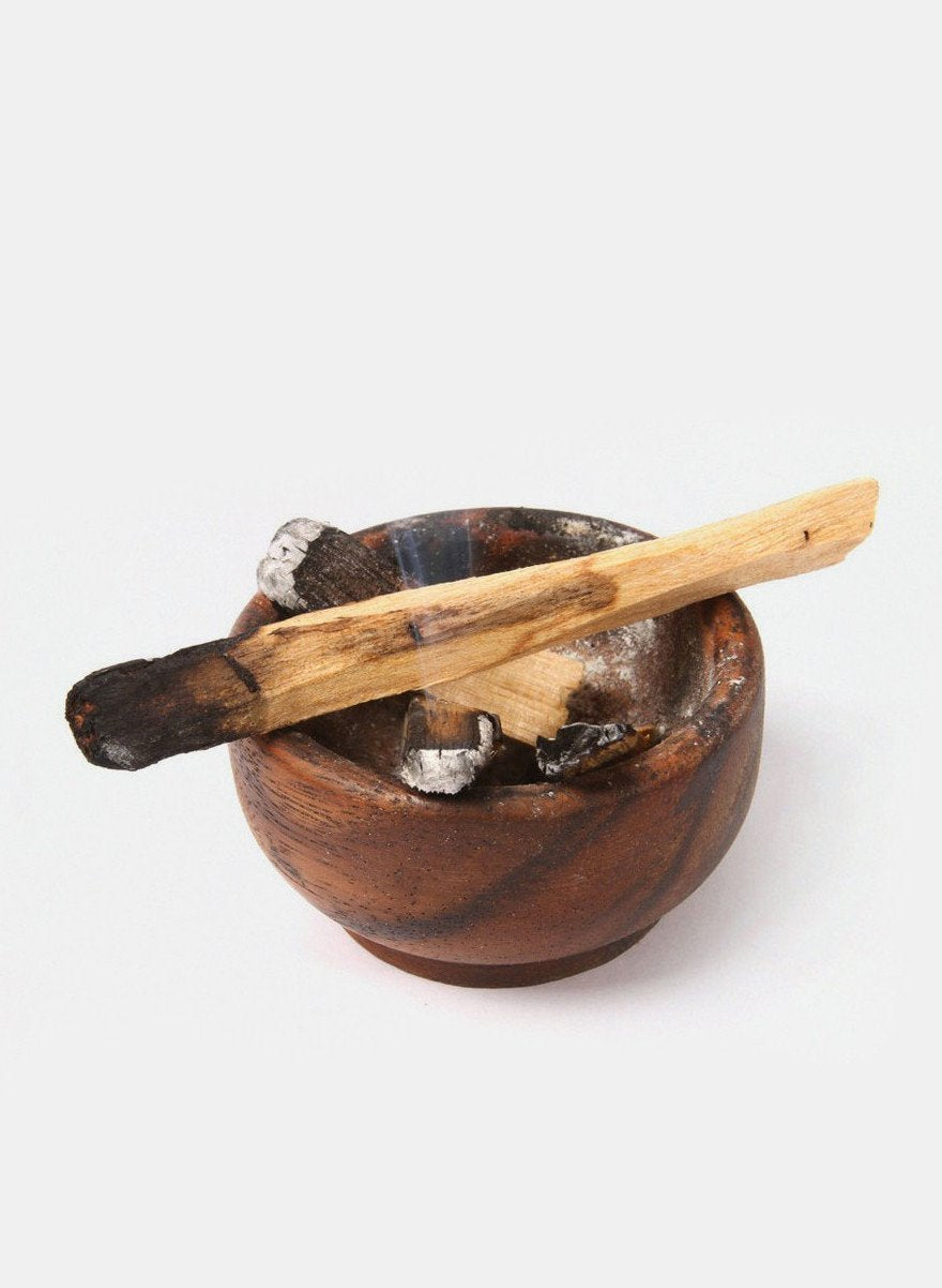 a bowl with a wooden stick and some ashes